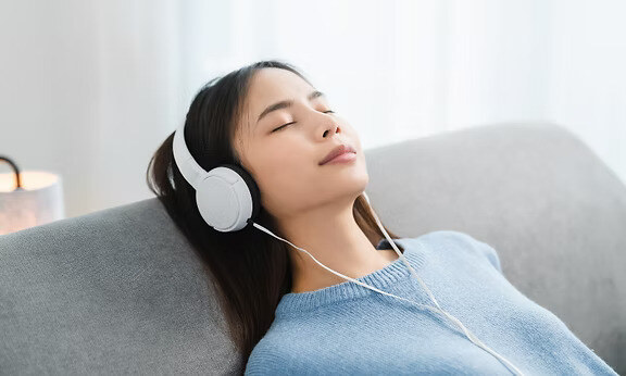 a woman lying on sofa and listening to music